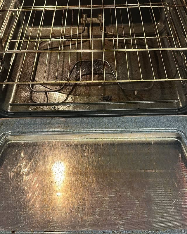 A client's oven before cleaning, grease and burnt residue on the oven floor and door glass